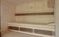 Massivholz-Sauna in Fichte mit Glasfront und Einrichtung in Nussbaum-Design