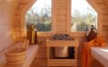 Große Fass-Sauna aus skandinavischer Fichte, außen dunkelrot lasiert, mit Vorraum, Einrichtung in Espe - Innenansicht, Saunabänke, große Fenster, Saunaofen und Saunazubehör