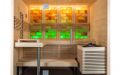 Kleine Massivholz-Sauna aus Fichte mit Glasfront, Infrarotstrahler und beleuchteter Salzsteinwand - Rückwand gelb-grün beleuchtet