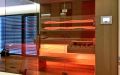 Glassauna mit Eckverglasung, Holzflächen in Wildeiche, Einrichtung in Thermo-Espe - LED Bank- und Rückenlehnenbeleuchtung, orange