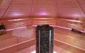 Saunakota aus Rundbohlen in Polarkiefer, Einrichtung in Espe - Innenansicht, Saunabänke mit farbiger LED-Bankbeleuchtung, großer zylindrischer Saunaofen