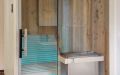 Kleine Badezimmer-Sauna mit abgeschrägter Glasfront; Innenverkleidung aus Altholzprofilen in Fichte, Tanne, Kiefer