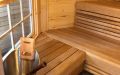 Kleine Saunakota aus Kiefernrundbohlen, außen rot und weiß gestrichen, Einrichtung in Thermoespe - Innenansicht linke Seite, Fenster, Aufgussgarnitur, Saunabänke