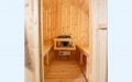 Fass-Sauna aus weißem Zedernholz mit kleiner Veranda - Blick in die Sauna mit Saunaofen