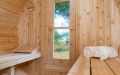 Fass-Sauna aus weißem Zedernholz mit kleiner Veranda - Innenansicht mit Kopfstütze, Saunatür und Liegetüchern