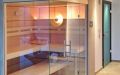 Wellness-Sauna mit Eckverglasung und integrierter Duschtrennwand - Durchblick zum beleuchteten Ofenschacht