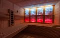 Massivholz-Sauna aus Fichte mit Glasfront, Infrarotstrahler und beleuchteter Salzsteinwand - Einrichtung und weiß-rot beleuchtete Rückwand